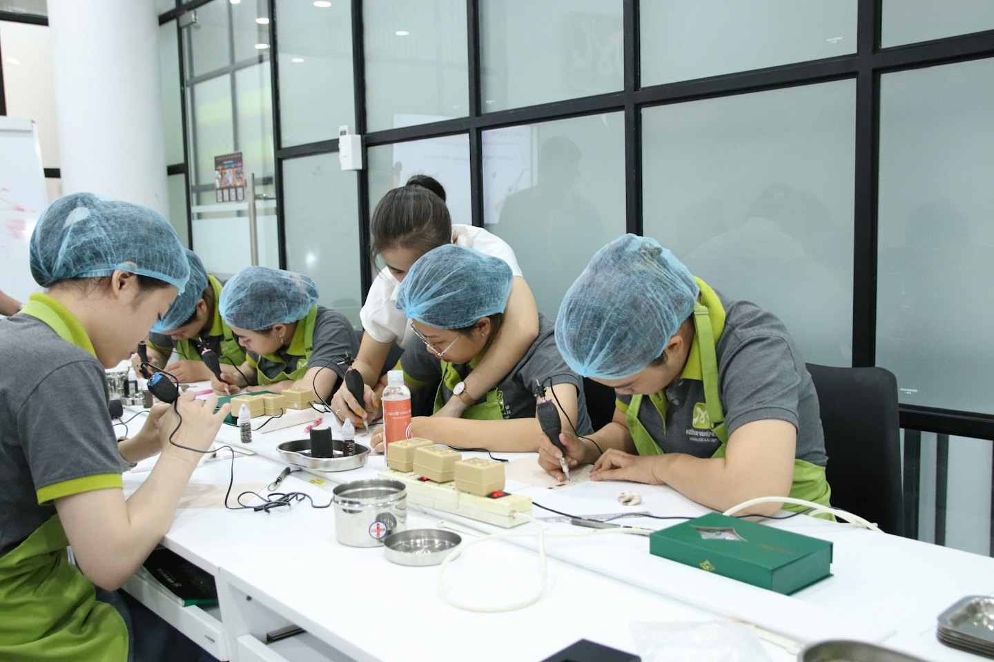 Instructor guides students practicing permanent makeup techniques on training blocks.